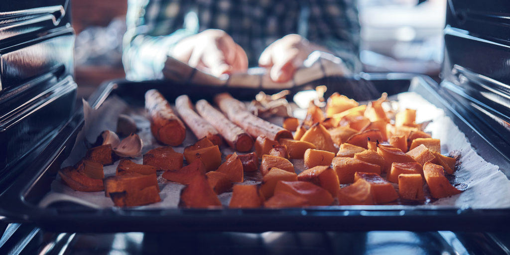 Someone pulling sweet potatoes out of the oven. Holiday meal